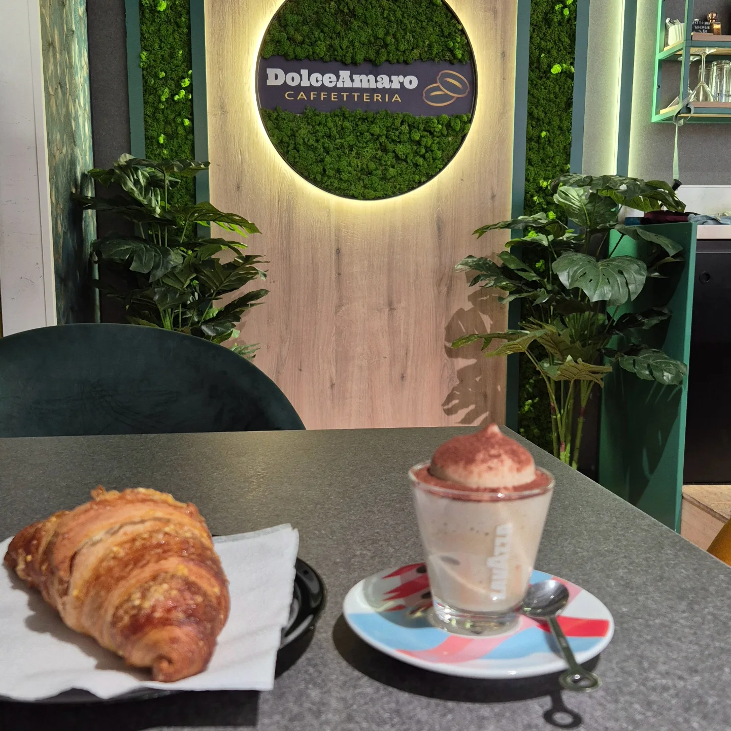 Cornetto und Crema di Caffè vor der beleuchteten Mooswand mit DolceAmaro-Logo